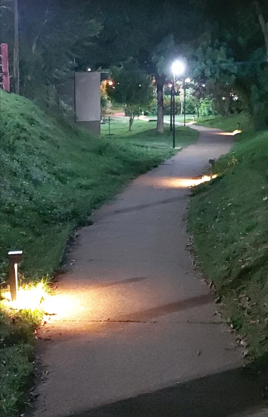 Alameda de caminhada iluminada entre as áreas verdes do condomínio