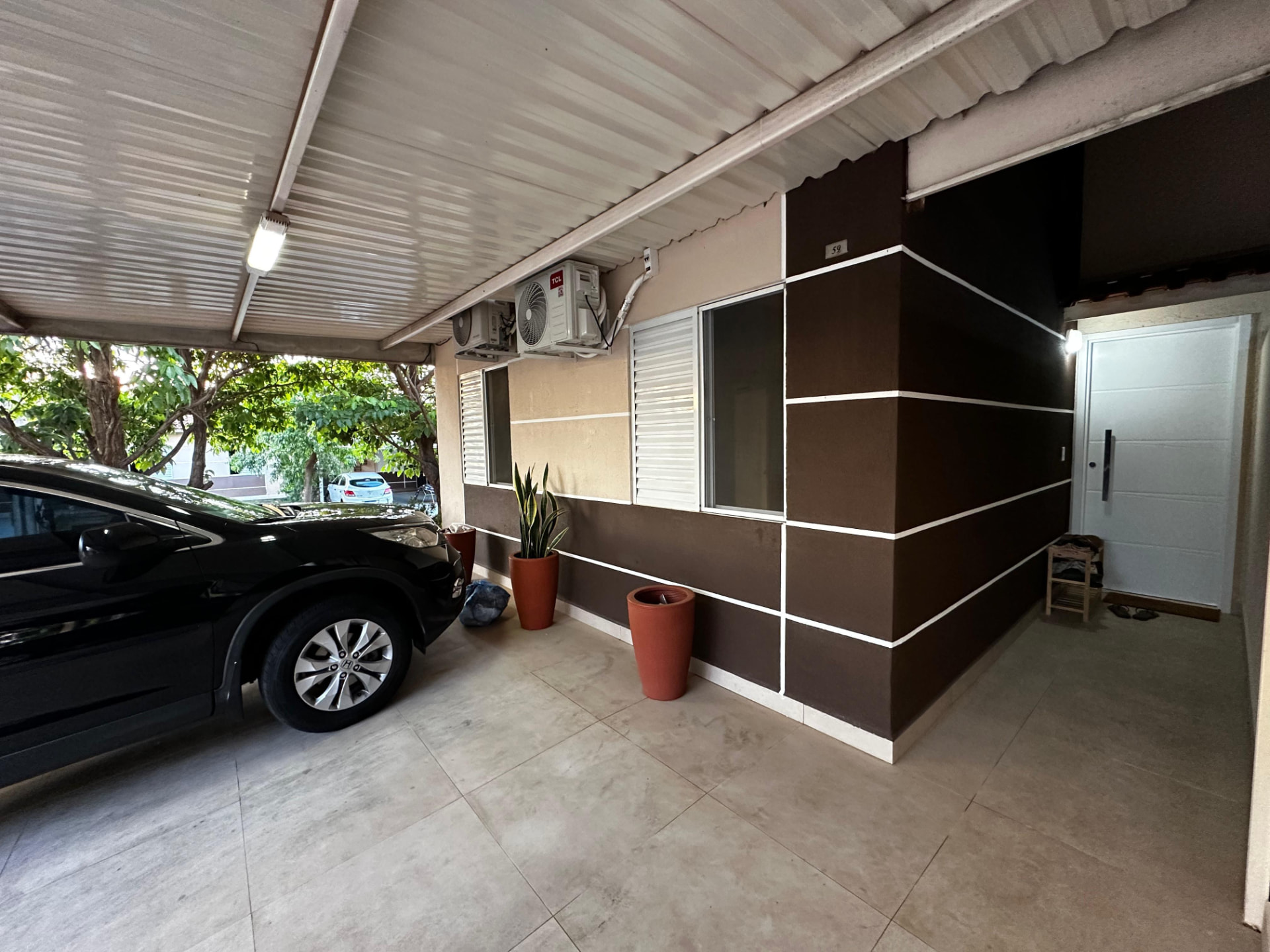 Entrada da casa com garagem coberta, fachada em tons de marrom e bege