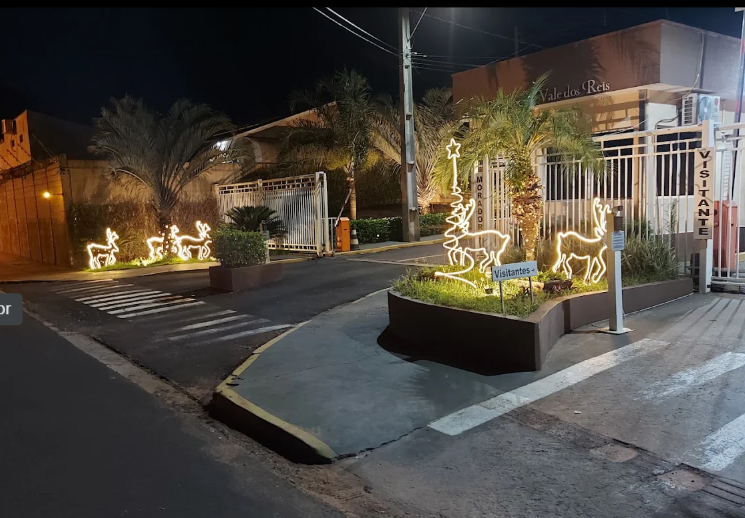 Entrada do condomínio à noite com decoração e acessos para moradores e visitantes